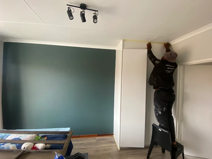 Illustrative painter working on ceiling trim